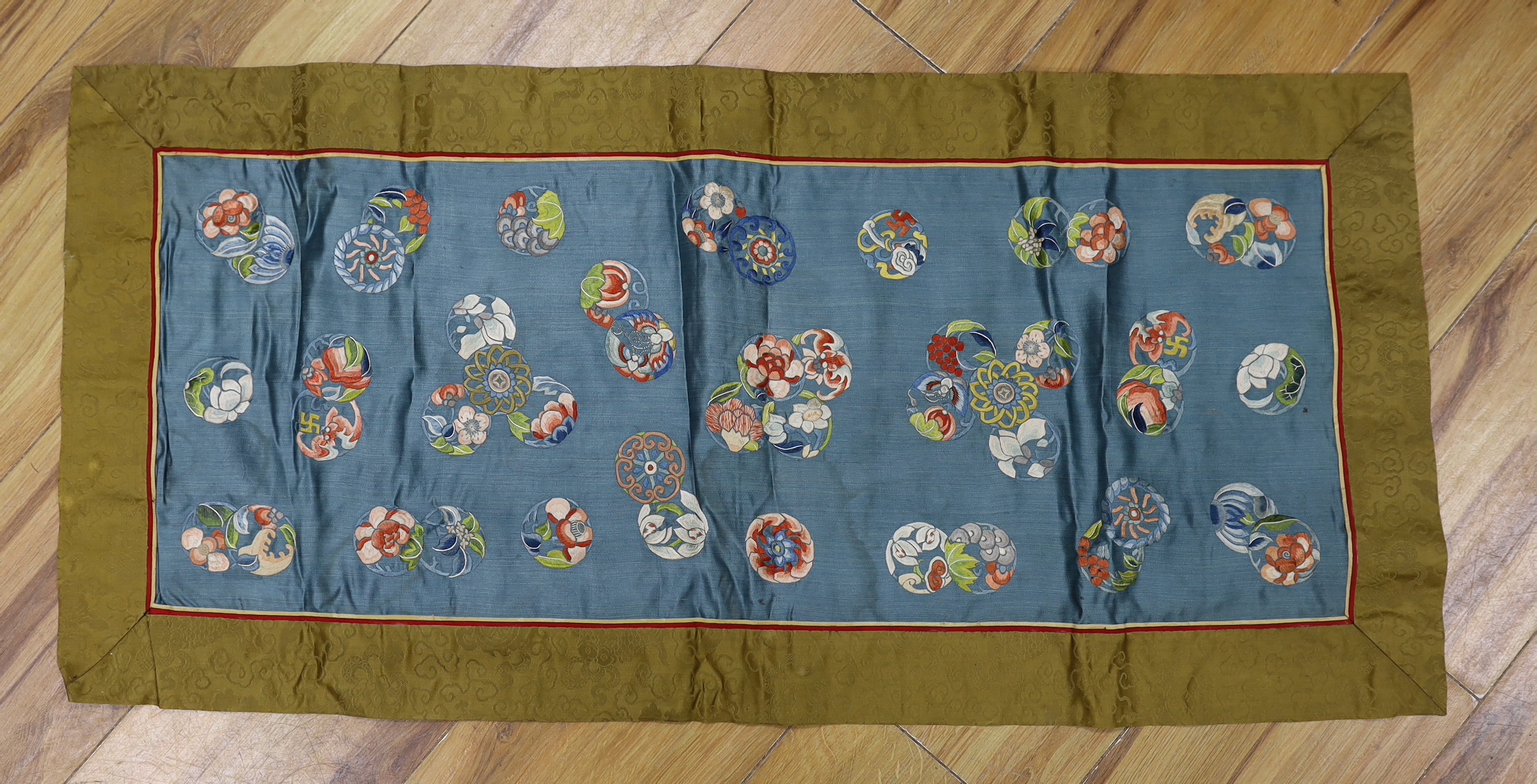 A long Chinese silk embroidered runner embroidered with the figure of Fu and boys, symbolic peaches, phoenix and flowers, possibly an altar cloth together with two other smaller runners, largest runner 202cm long x 55cm